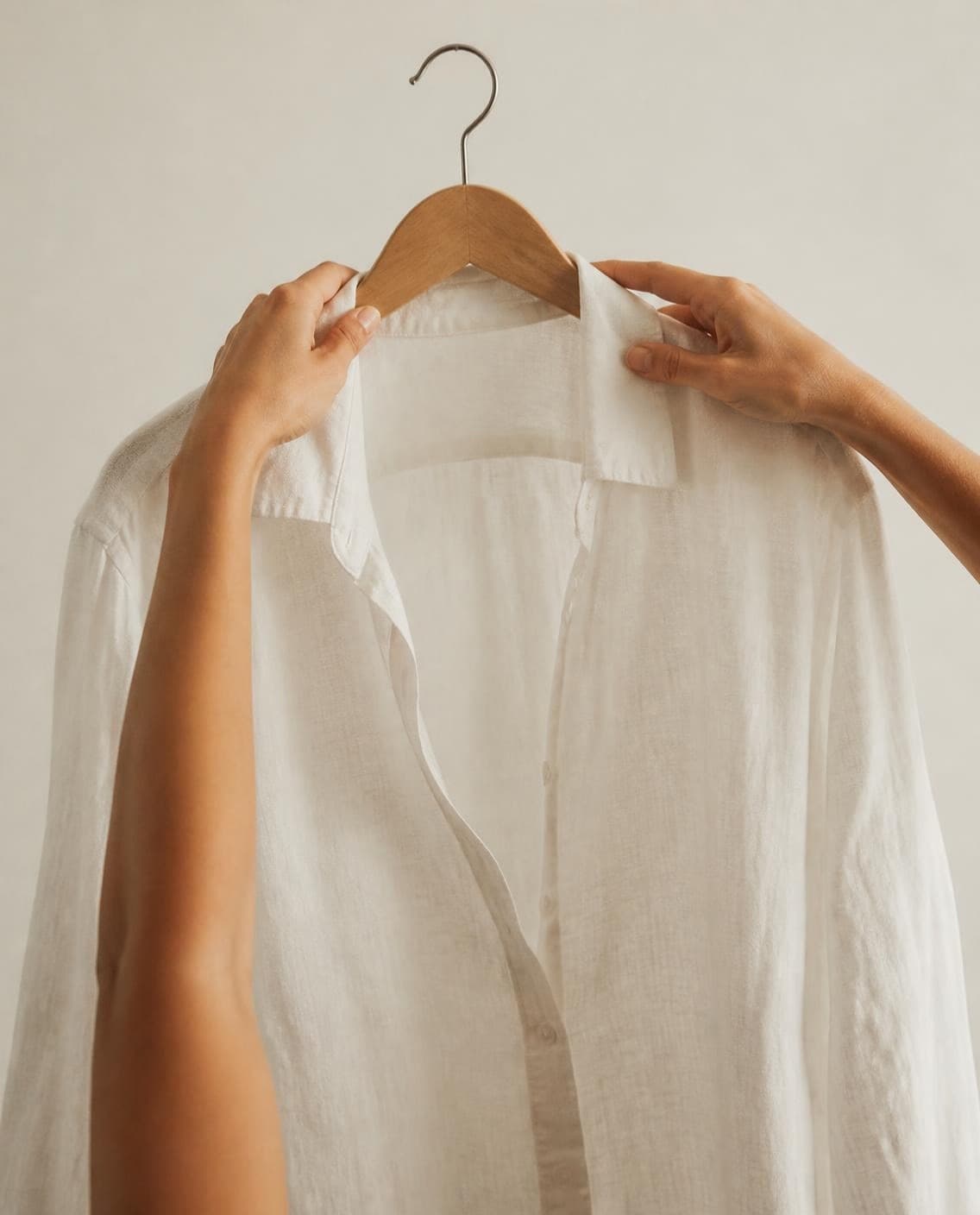 Hands holding a white linen shirt on a hanger (a generated photo)