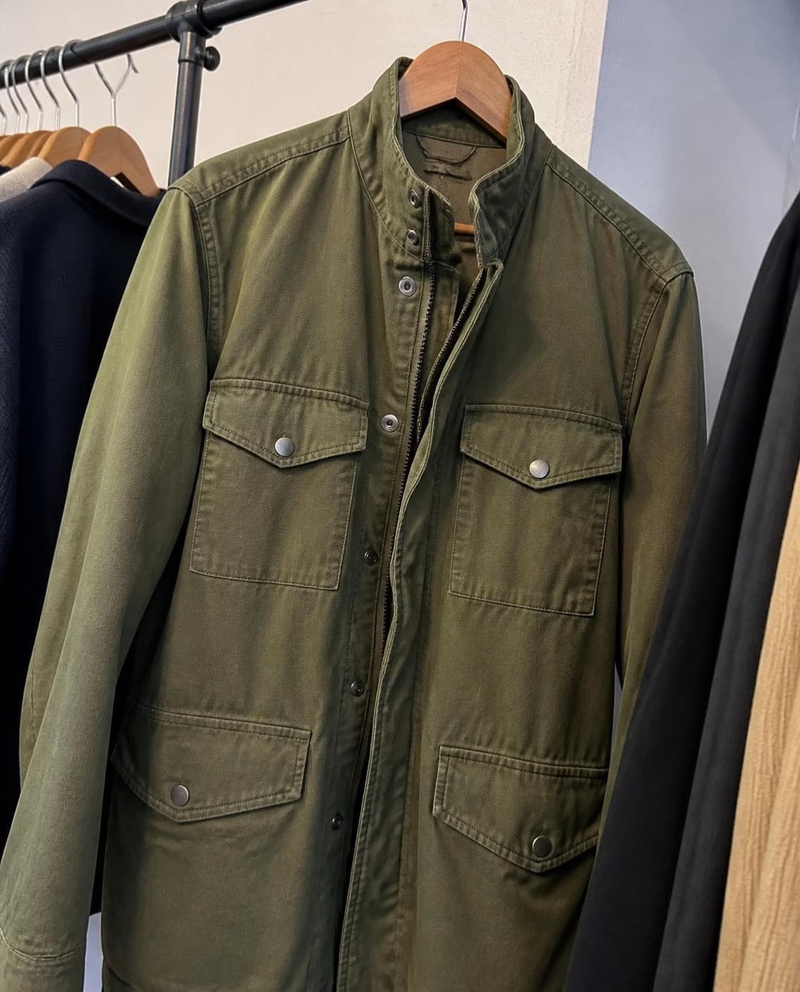 An olive field jacket on a shop rail (a generated photo)